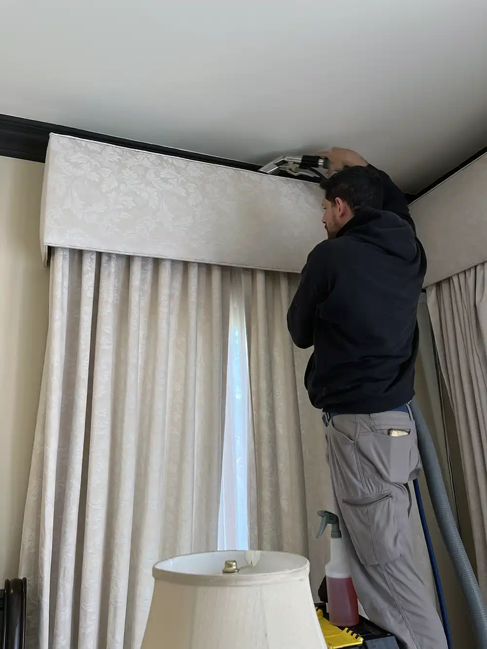 Green Scrub technician professionally cleaning an upholstered window valance